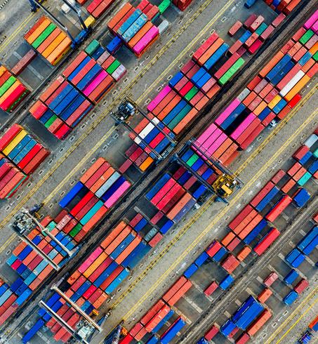 Aerial view of a busy shipping container yard, filled with colorful stacked containers.
